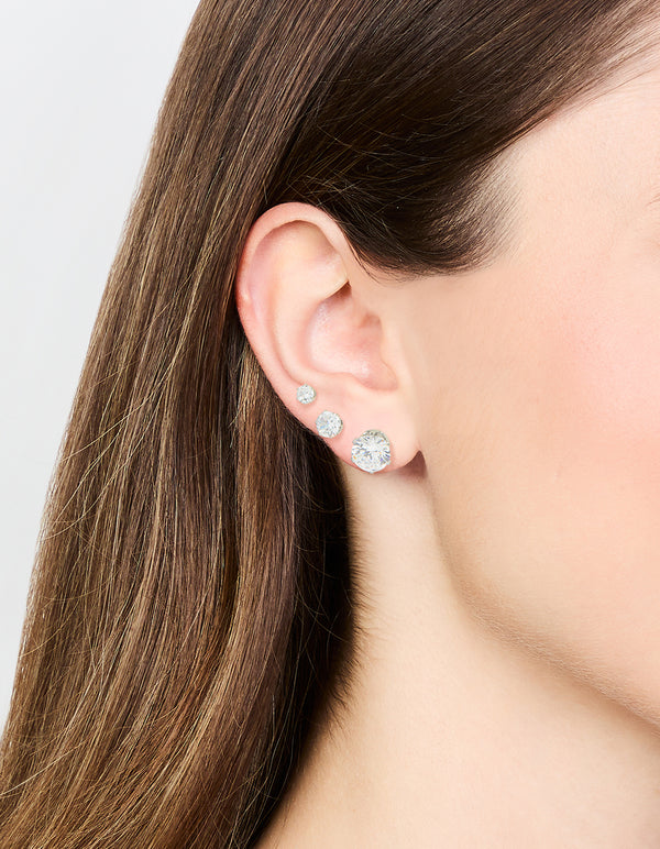 Featuring waterproof stainless steel graduating cubic zirconia earring 3-pack with stud closure in silver on ear view