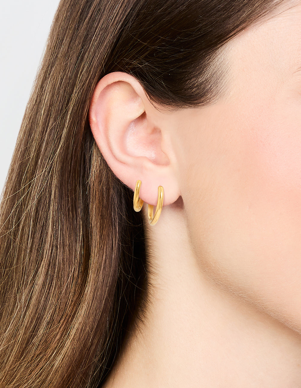 Showcasing waterproof gold plated stainless steel small hoop earrings in a 2-pack on ear view