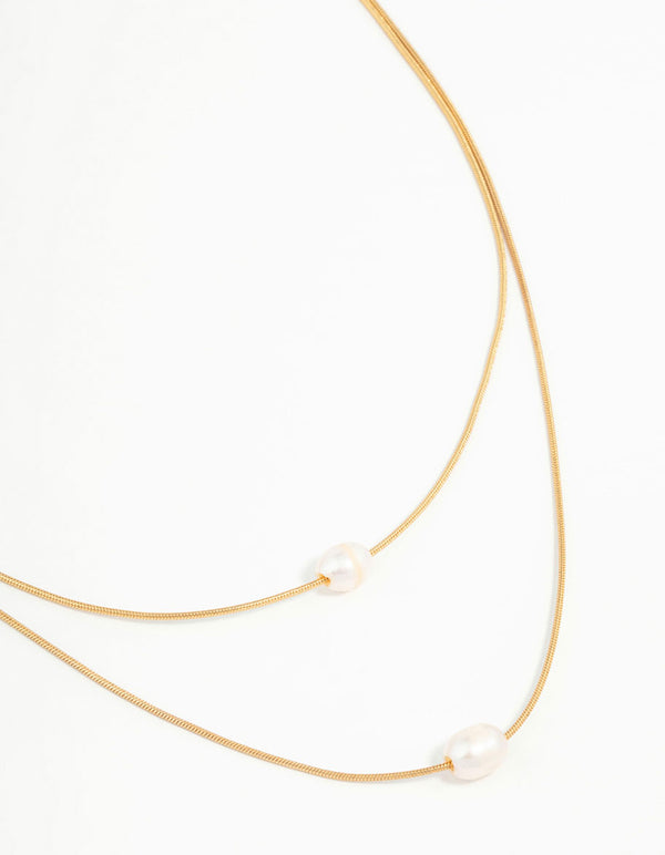 Showcasing a waterproof gold plated stainless steel layered pearl pendant necklace in a close up view