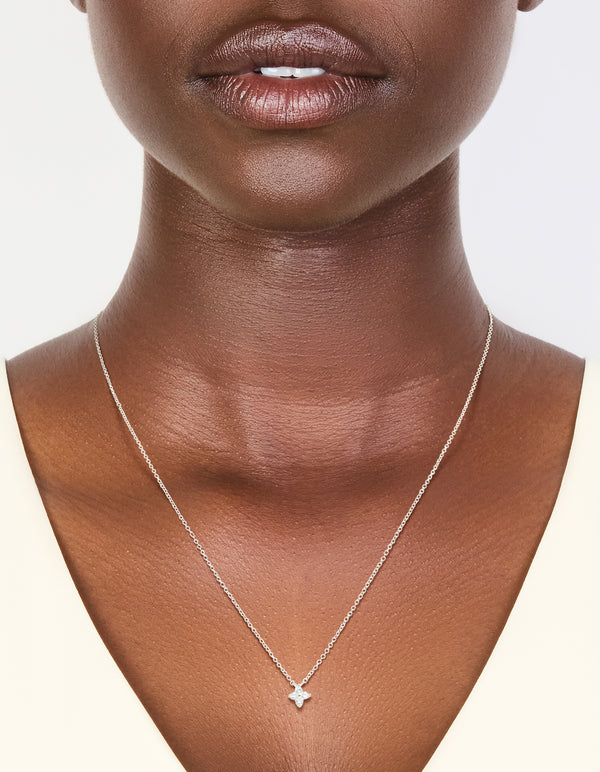 Featuring a sterling silver cubic zirconia micro flower pendant in dainty on neck view