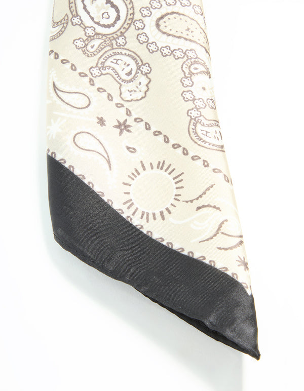 An elegant fabric scarf with paisley print in beige, tan, and black highlighting corner side view