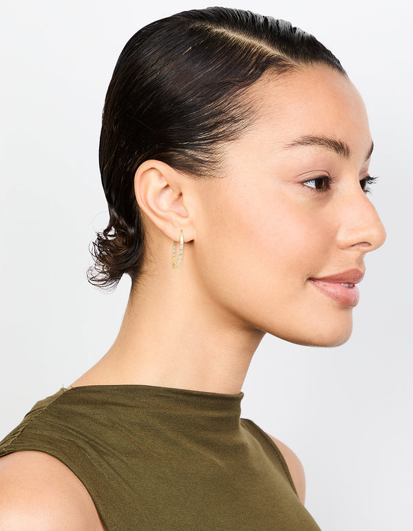 Designed with cubic zirconia stones, these gold plated statement large skinny hoop earrings are displayed on model view