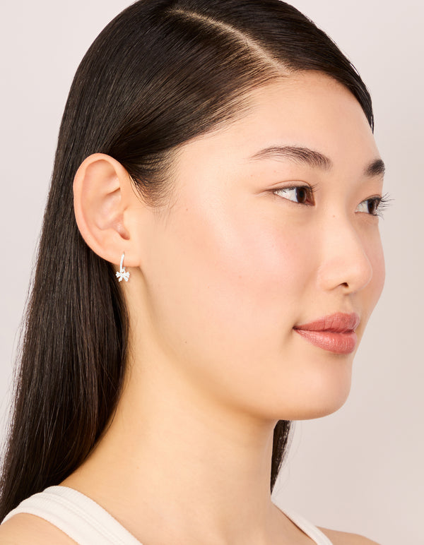 Presenting sterling silver cubic zirconia bow huggie earrings on model view