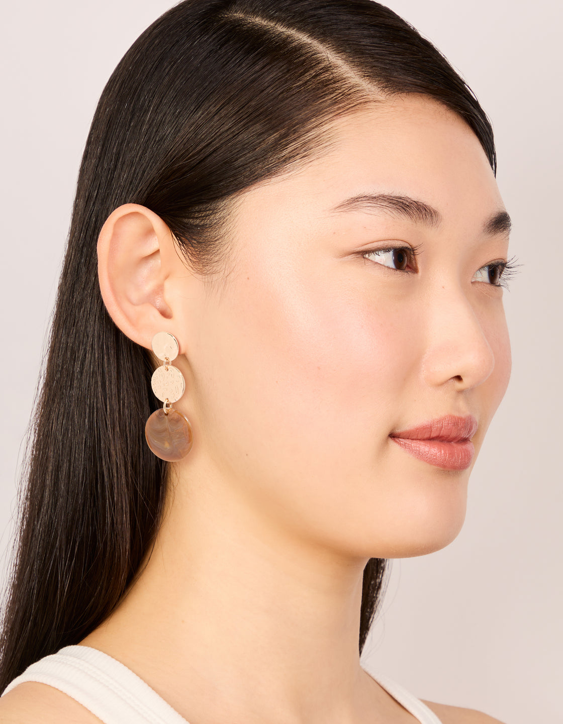 Displaying gold molten and brown stone round drop earrings with statement style on model view