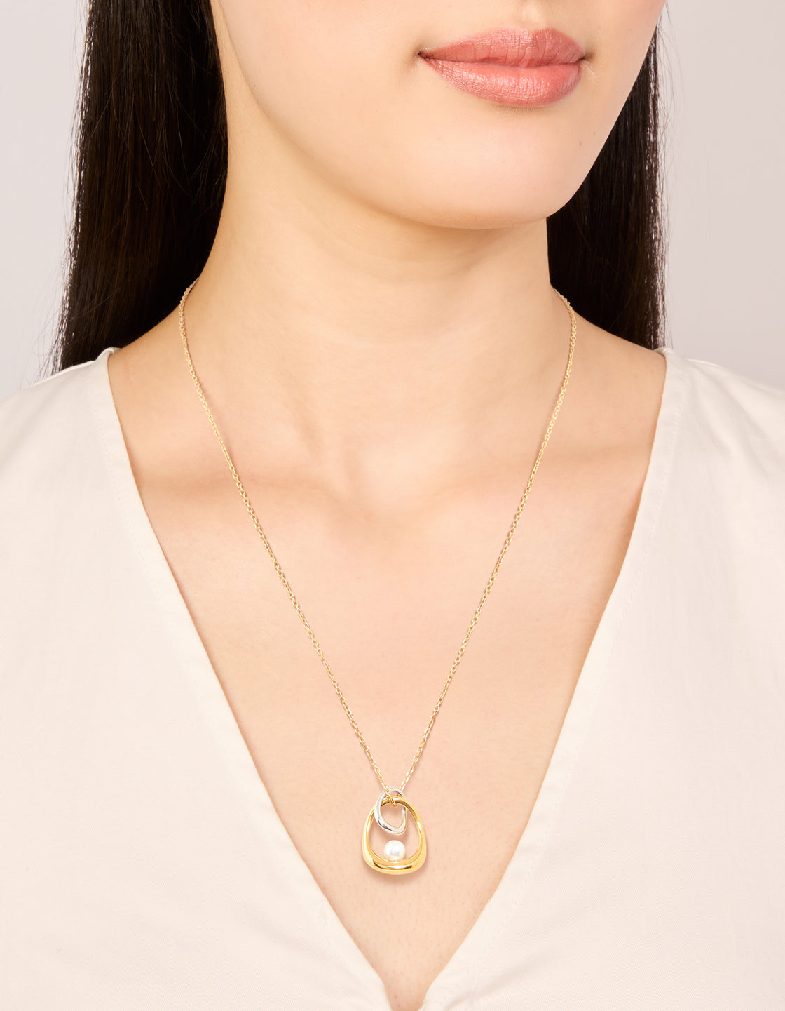 Featuring this waterproof mixed metal plated stainless steel open pearl pendant necklace with oval stone cut in gold and silver on neck view