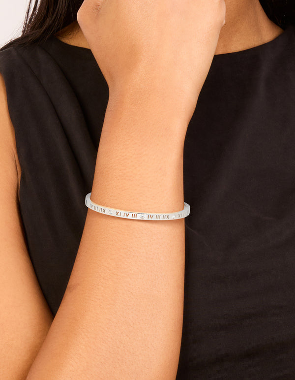 Showcasing a waterproof stainless steel diamante Roman numeral hinge bangle in silver with clear stones on wrist view