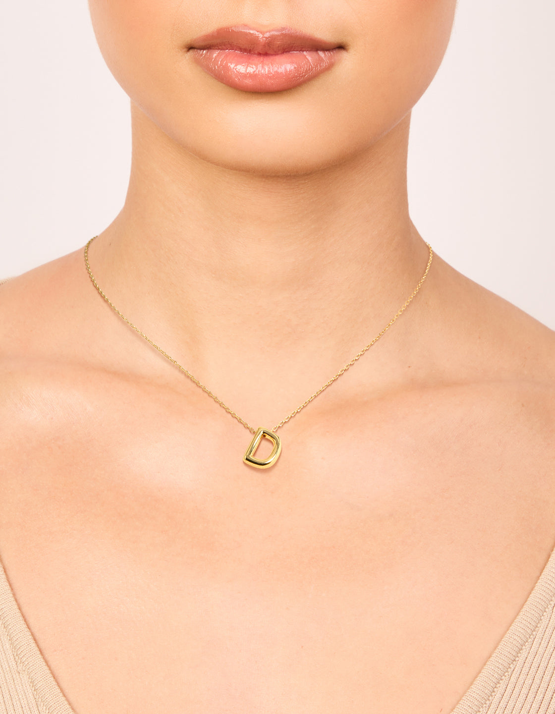 Showcasing a gold plated bubble letter D necklace with initials featuring pendant in dainty style on neck view