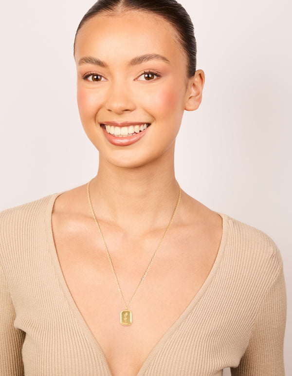 Showcasing a waterproof December birth flower poinsettia necklace featuring floral detail in gold plated stainless steel on model view