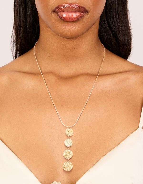 Showcasing a waterproof stainless steel necklace with gold plated discs charms featuring dimple texture on neck view