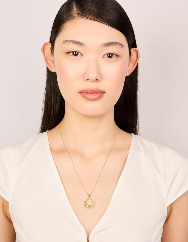 Showcasing this celestial statement necklace in waterproof gold plated stainless steel with sunburst pendant on model view