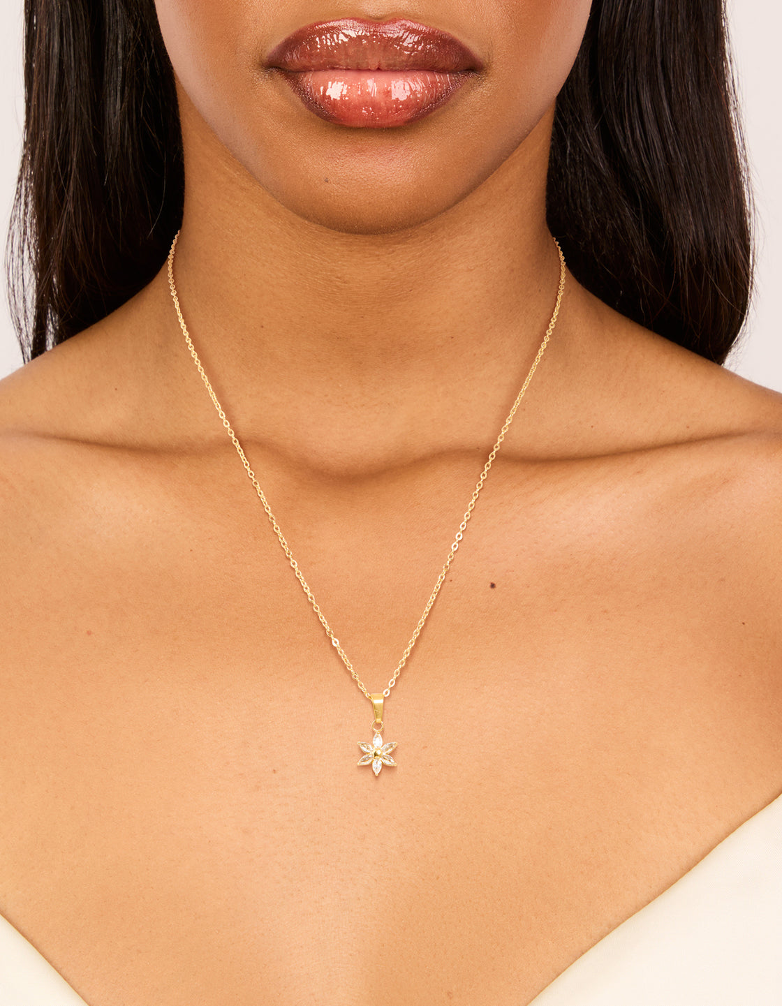 Showcasing a waterproof floral pendant necklace crafted from gold plated stainless steel with cubic zirconia crystal accents on neck view