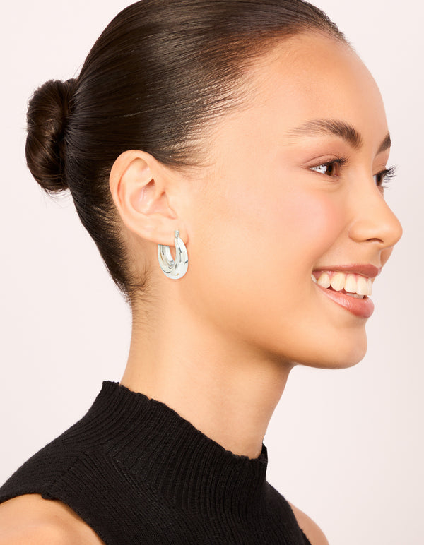 Displaying waterproof stainless steel small chunky huggie earrings with closure in silver on model view