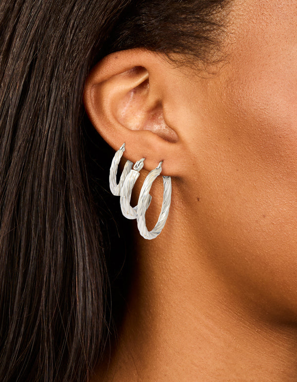 Featuring waterproof stainless steel twisted hoop earrings in a 3-pack with silver finish on ear view