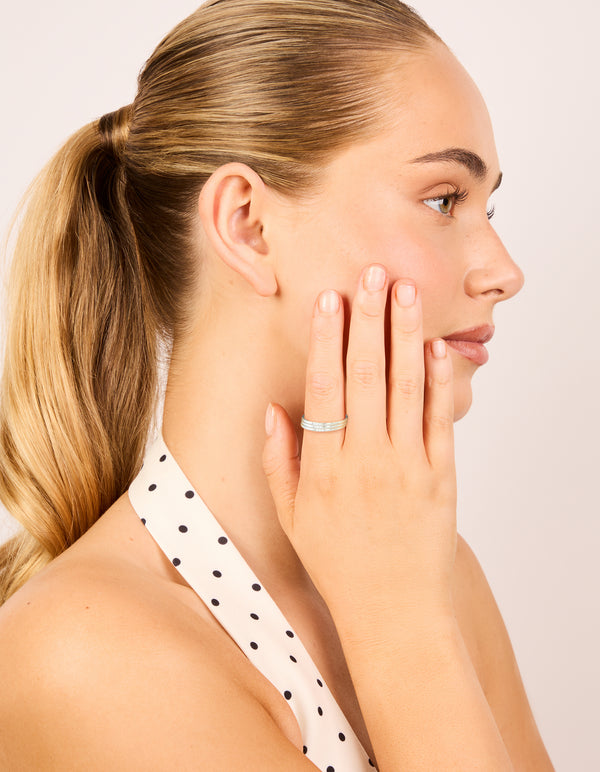 Featuring waterproof stainless steel with cubic zirconia accents, this thin trio rings 3-pack in silver and clear stone on finger view