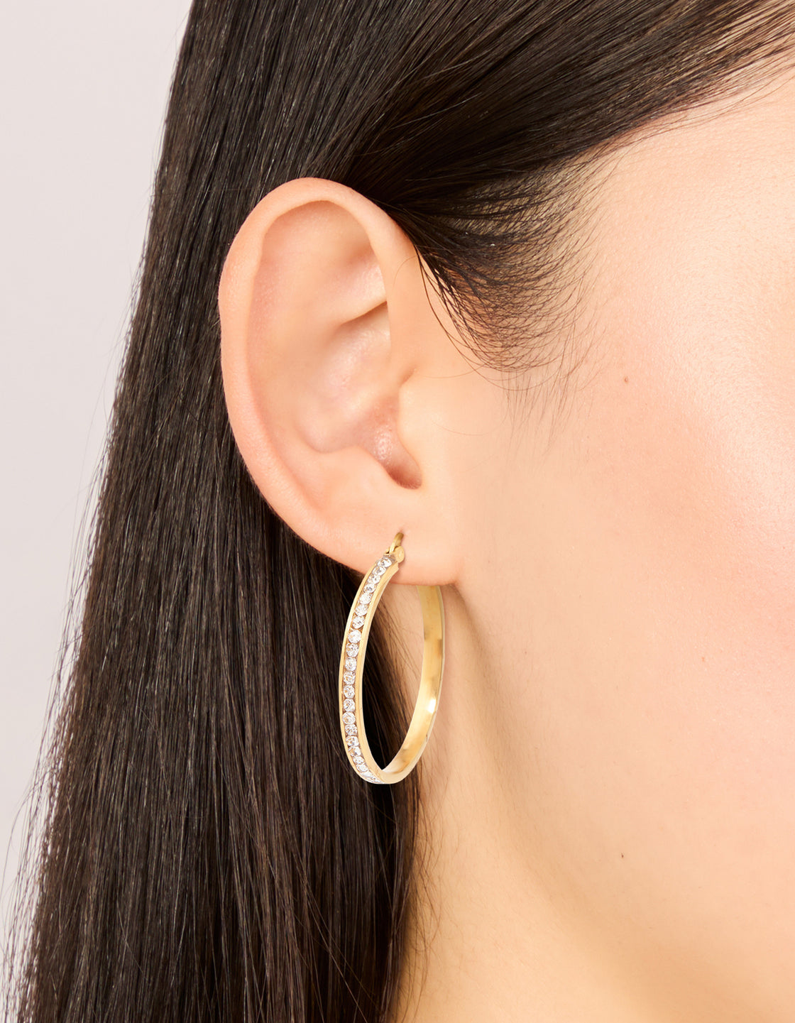 Crafted from gold plated waterproof stainless steel diamante hoop earrings on ear view