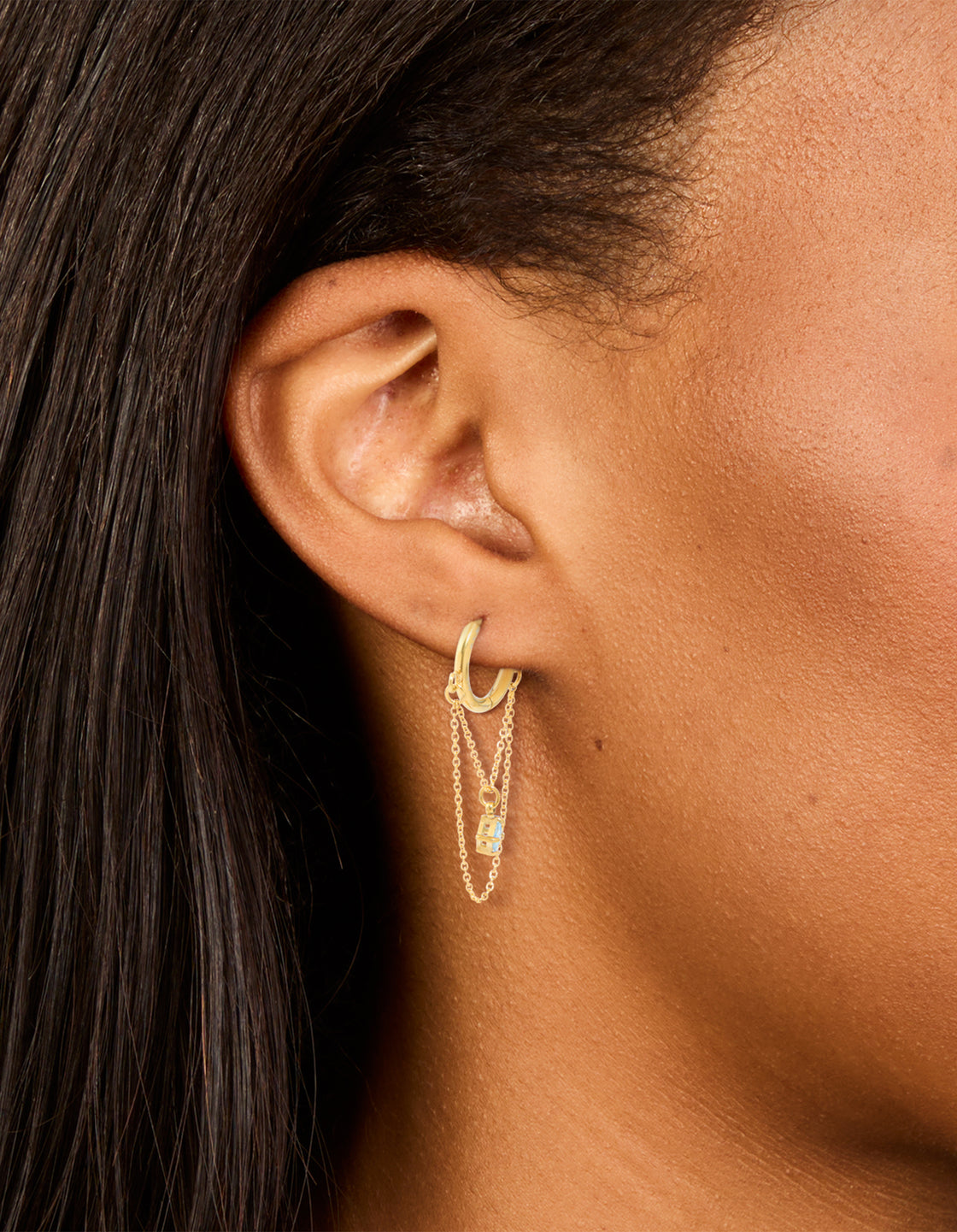 Designed with waterproof gold plated stainless steel, these huggie earrings and cubic zirconia accents, huggie closure in light blue on ear view