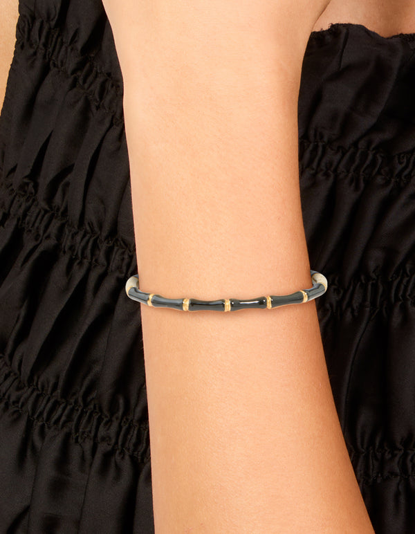 Showcasing a waterproof gold plated stainless steel black enamel bamboo bangle with statement design on wrist view
