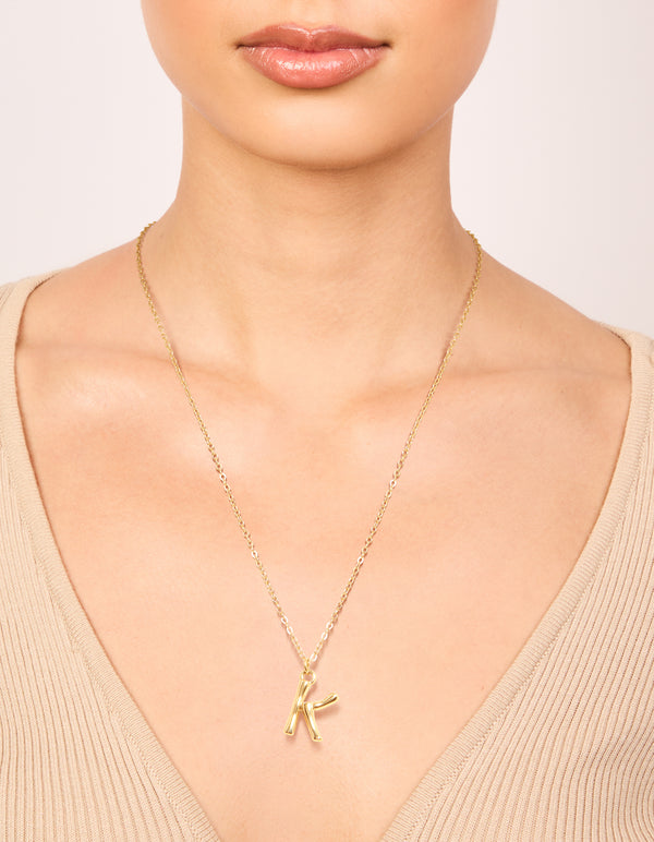 Showcasing a waterproof bamboo letter K initial pendant necklace in gold plated stainless steel on neck view
