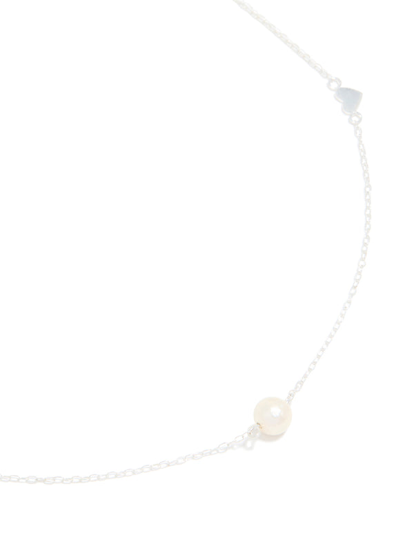 Showcasing a sterling silver necklace featuring heart and pearl in a delicate design close up view