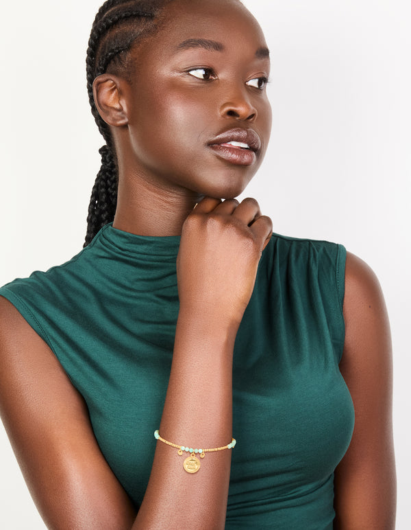 Crafted with a waterproof beaded bracelet crafted from gold plated stainless steel, featuring aquamarine beads and script charms in a dainty style on model view