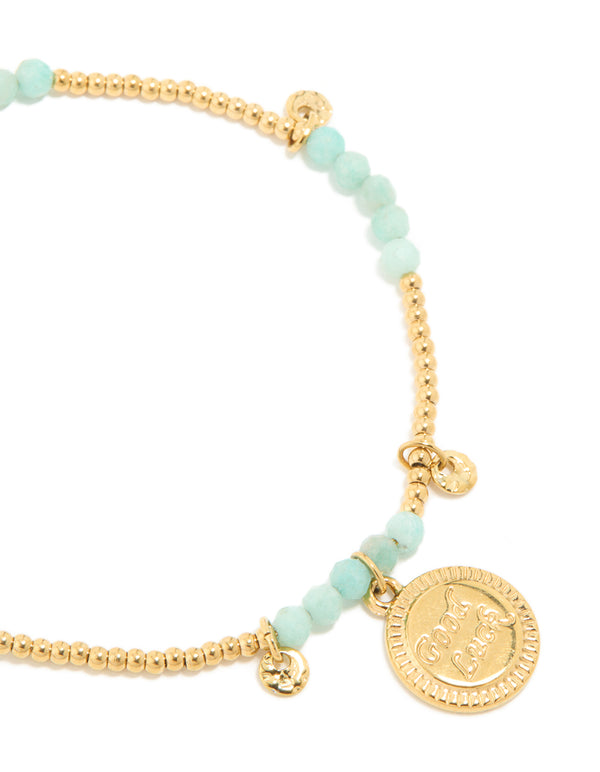 Highlighting a waterproof beaded bracelet crafted from gold plated stainless steel, featuring aquamarine beads and script charms in a dainty style in a close up view