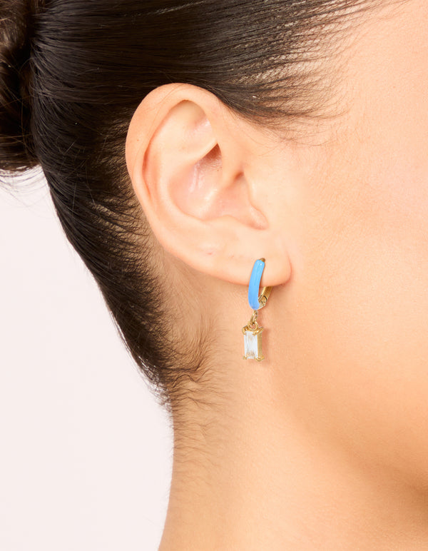 Featuring waterproof gold plated huggie earrings with light blue enamel and cubic zirconia charm on ear view