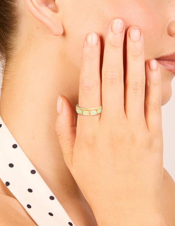 Showcasing a gold plated vintage statement ring featuring pale green pebbles on finger view