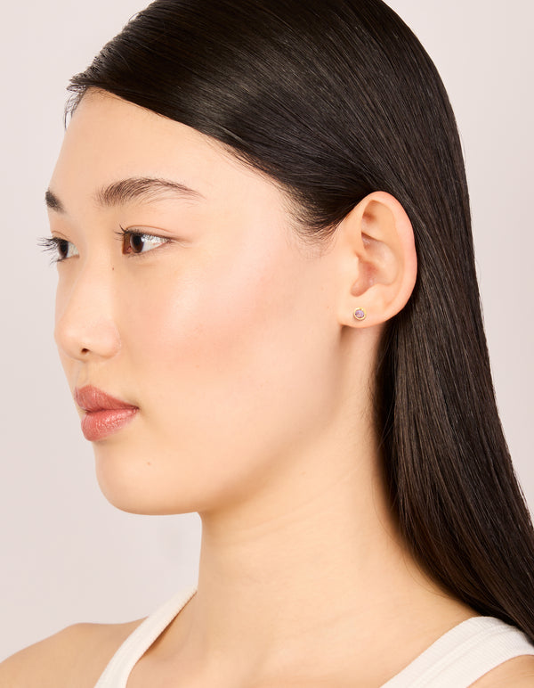 Stylish waterproof bezel set stud earrings featuring lavender cubic zirconia in gold plated stainless steel on model view