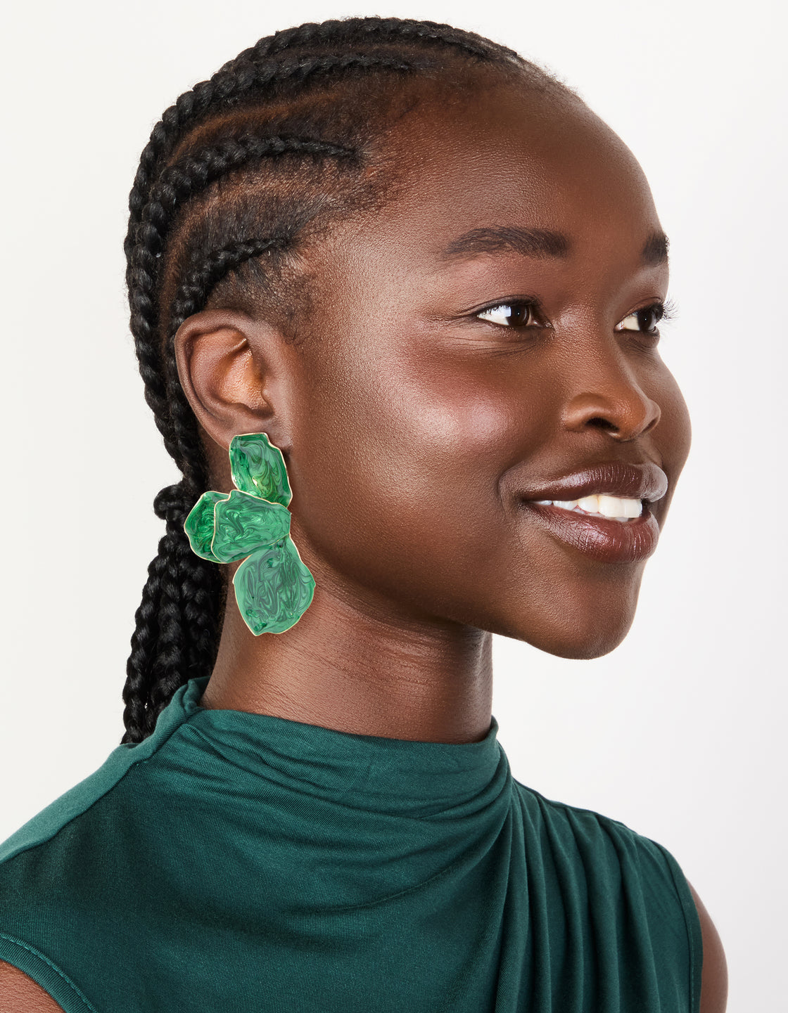 Crafted from emerald green coated metal half flower petal drop earrings in statement style worn on model view