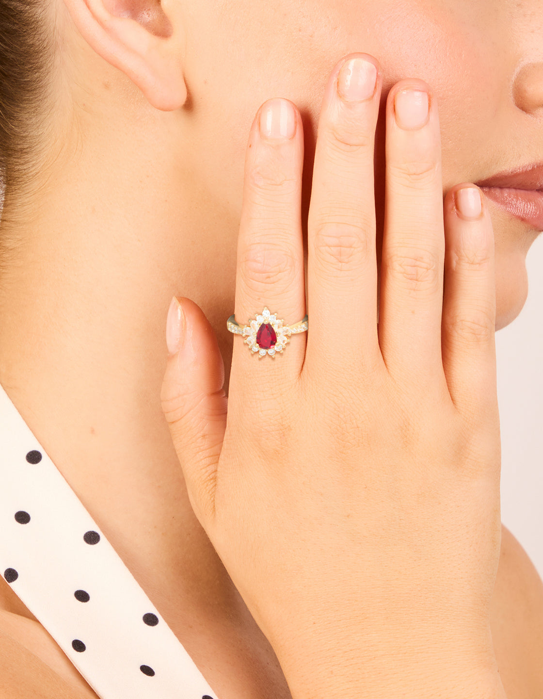 Elegant gold plated gleaming red cubic zirconia ring with pear stone cut in statement style on finger view