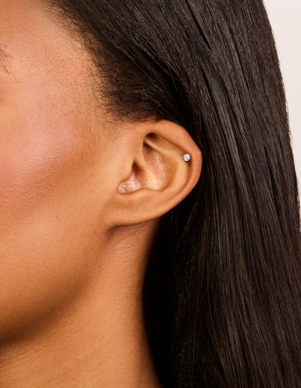 Showcasing sterling silver round cubic zirconia single flat back stud earrings with crystal on ear view