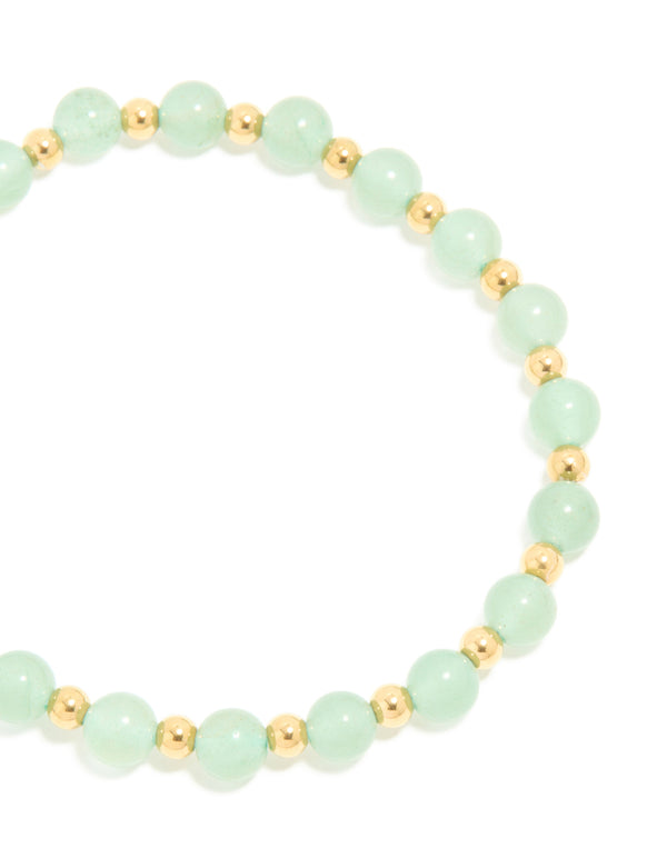 Highlighting a waterproof beaded stretch bracelet crafted from gold plated stainless steel with pale green beads close up view
