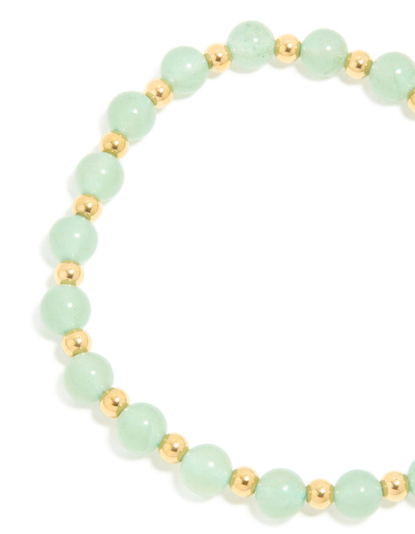 Highlighting a waterproof beaded stretch bracelet crafted from gold plated stainless steel with pale green beads close up view