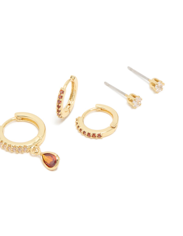 Product showcases gold plated brass ruby cubic zirconia July birthstone 4-pack earrings designed with crystal, stud, huggie and hoop closures in dark orange and clear post detail view