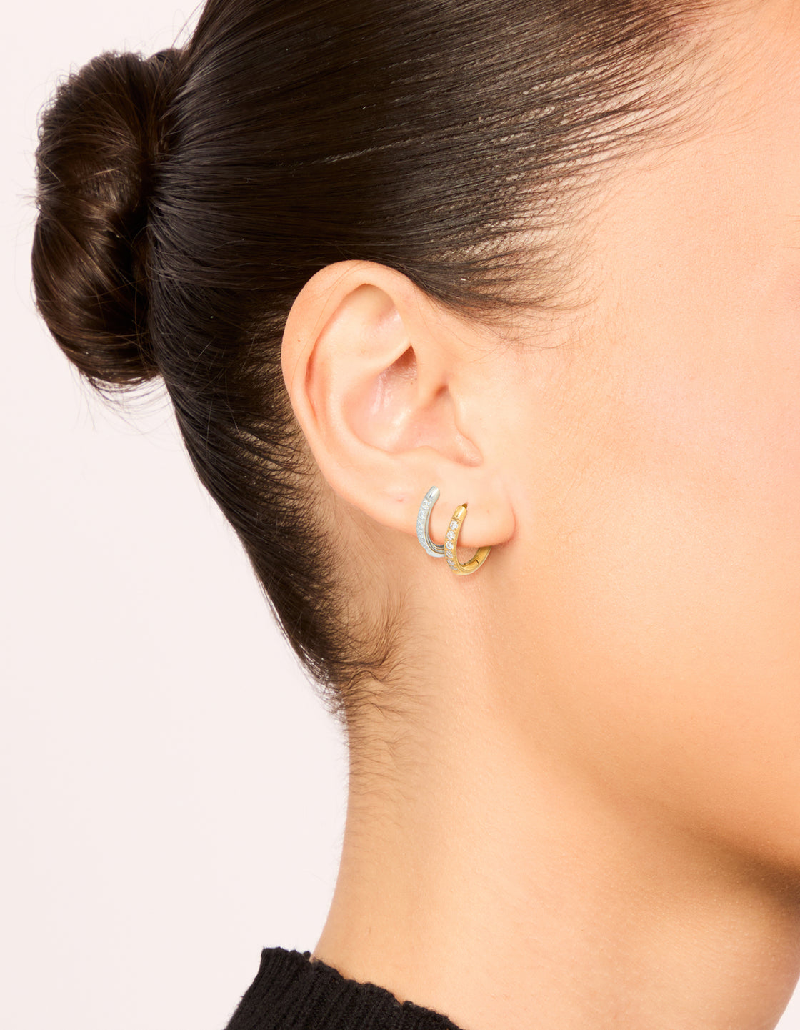 Showcasing waterproof thin pavé huggie earrings in a 2-pack crafted from stainless steel with cubic zirconia and gold plated on ear view