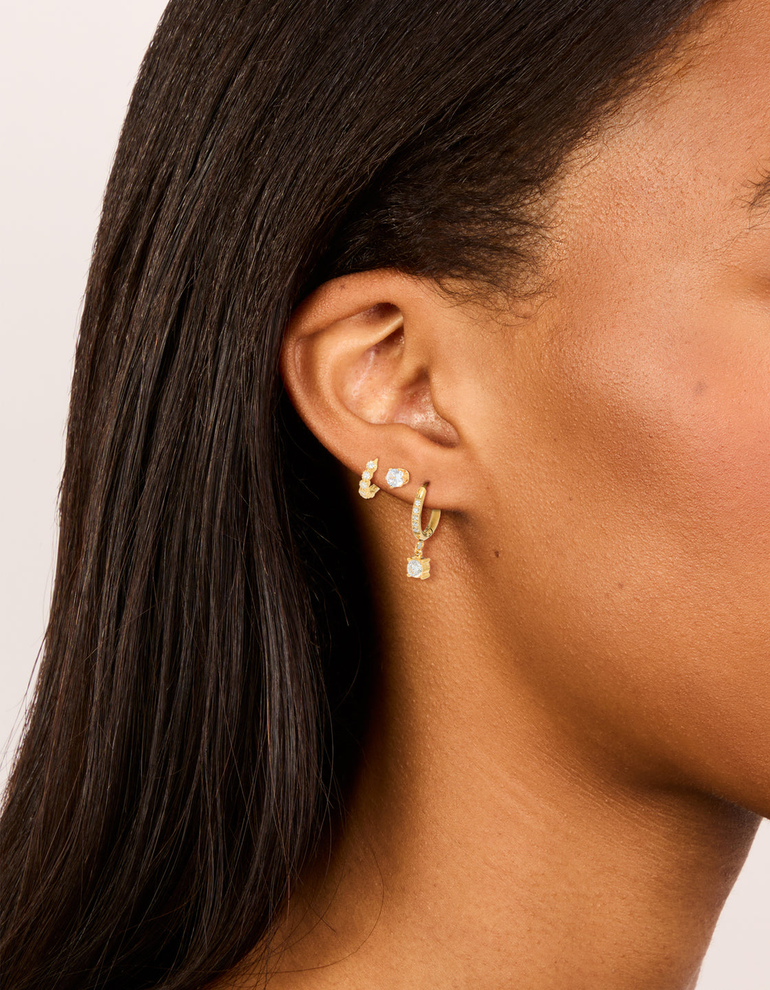 Showcasing waterproof gold plated stainless steel cubic zirconia stud and huggie earrings in a 3-pack featuring crystal on ear view