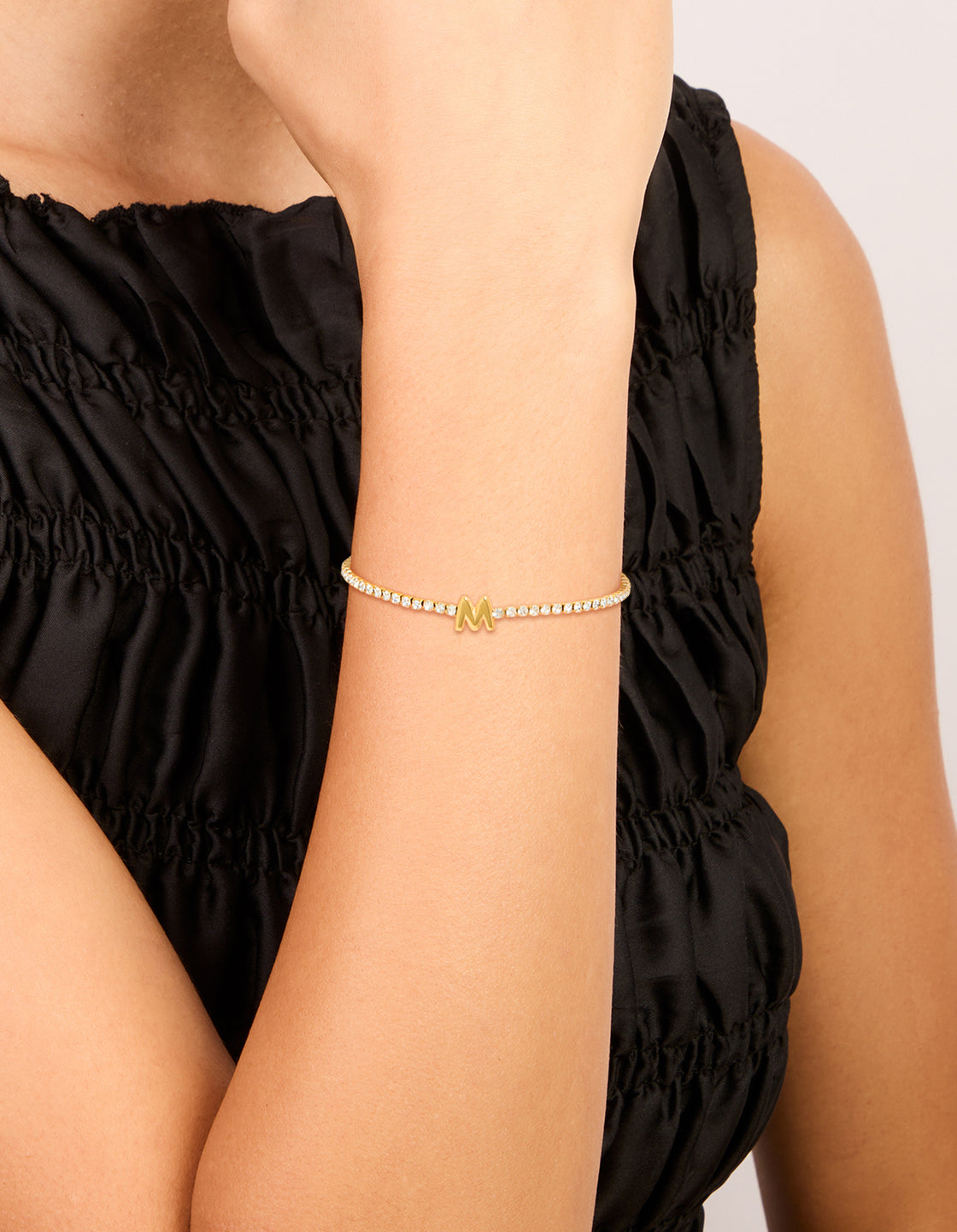 Showcasing a waterproof gold plated stainless steel cubic zirconia with letter M initial tennis bracelet on wrist view