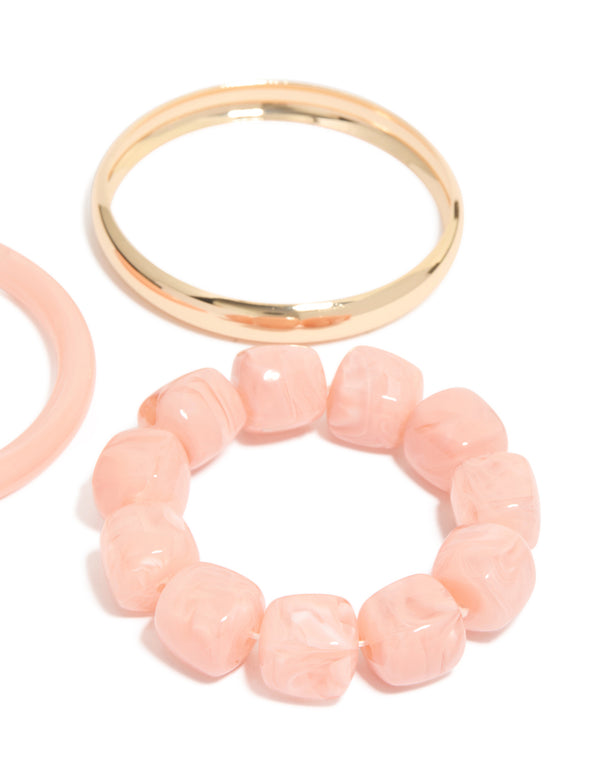 Featuring pink acrylic and gold smooth bangles 3-pack with beaded bracelet detail in close up view