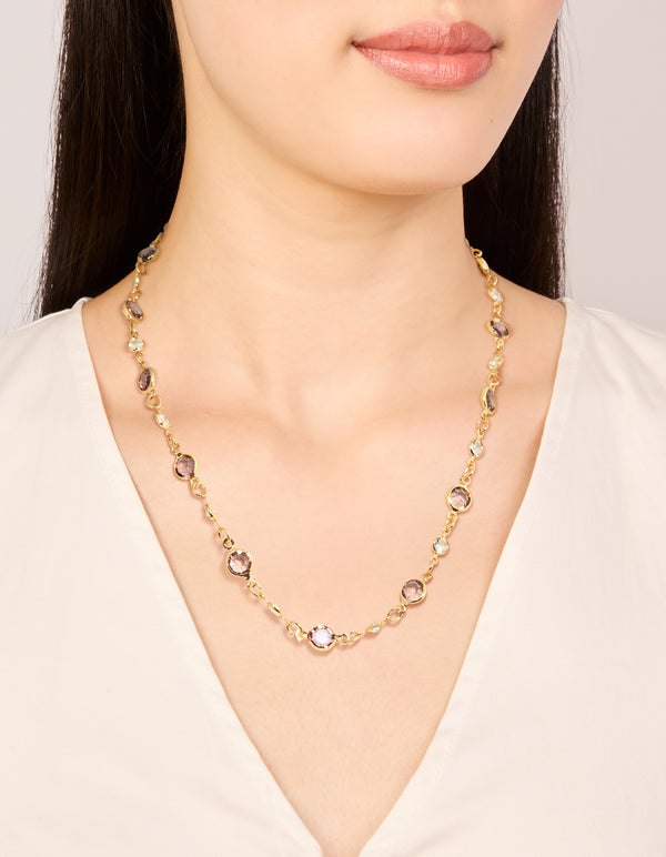 Showcasing a gold plated station necklace with pink and clear cubic zirconia stones in round cut on neck view