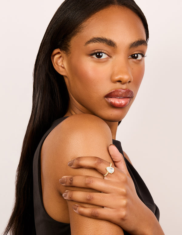 Showcasing a statement ring crafted from gold plated crystal featuring a solitaire pear cubic zirconia on finger view