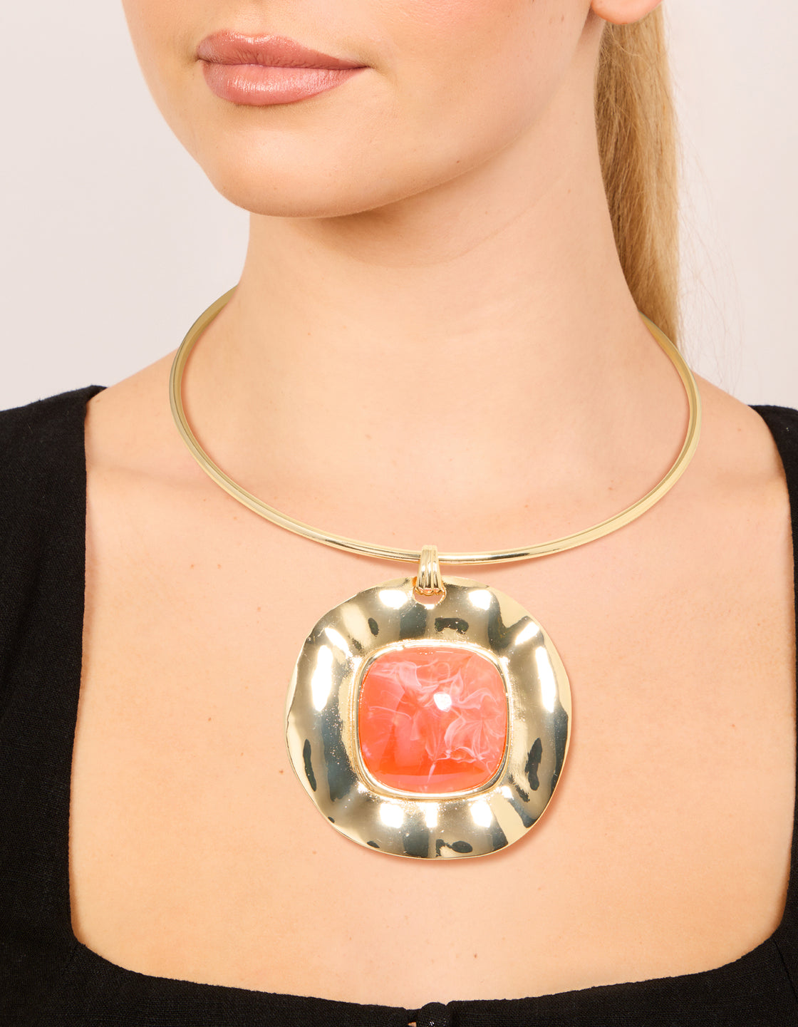 Showcasing a gold orange pendant choker torque necklace with statement styling on neck view