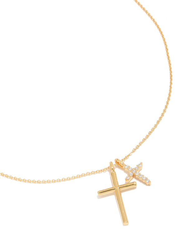 Showcasing a brass double cross necklace with charm featuring cubic zirconia in gold plated finish, statement pendant style close up view
