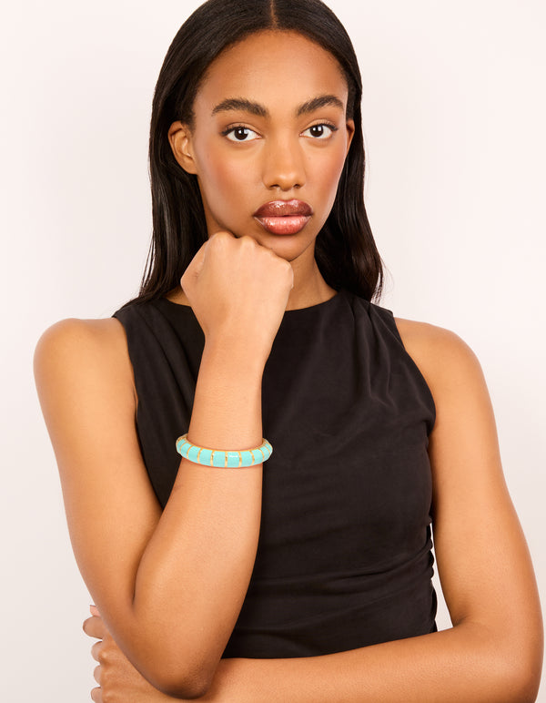 Showcasing this waterproof ribbed blue enamel bangle crafted from stainless steel with gold plating on model view