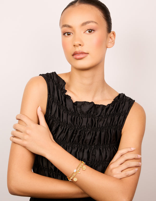 Showcasing waterproof gold plated stainless steel freshwater pearl and multicoloured cord charm bracelets featuring celestial sun, shell, coin, rose quartz, and beads in a 2-pack on model view