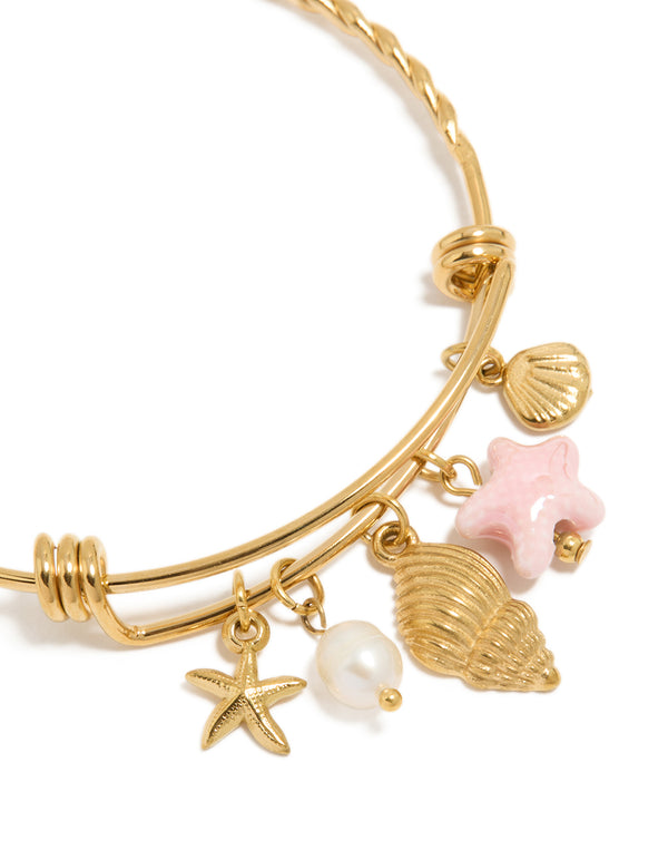 Showcasing waterproof gold plated stainless steel adjustable bangle with starfish charm, shell, ocean and pearl accents close up view