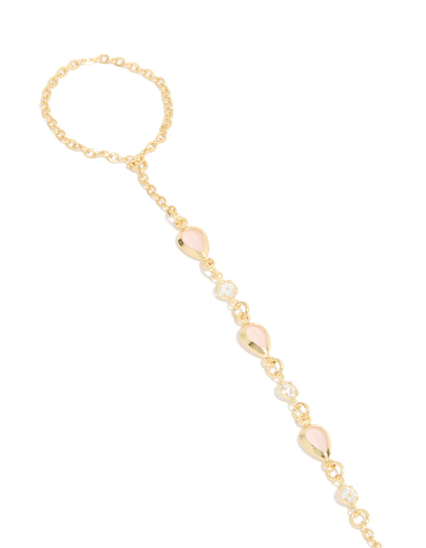 Crafted from gold plated material, this pink cubic zirconia teardrop hand chain bracelet in statement design close up view