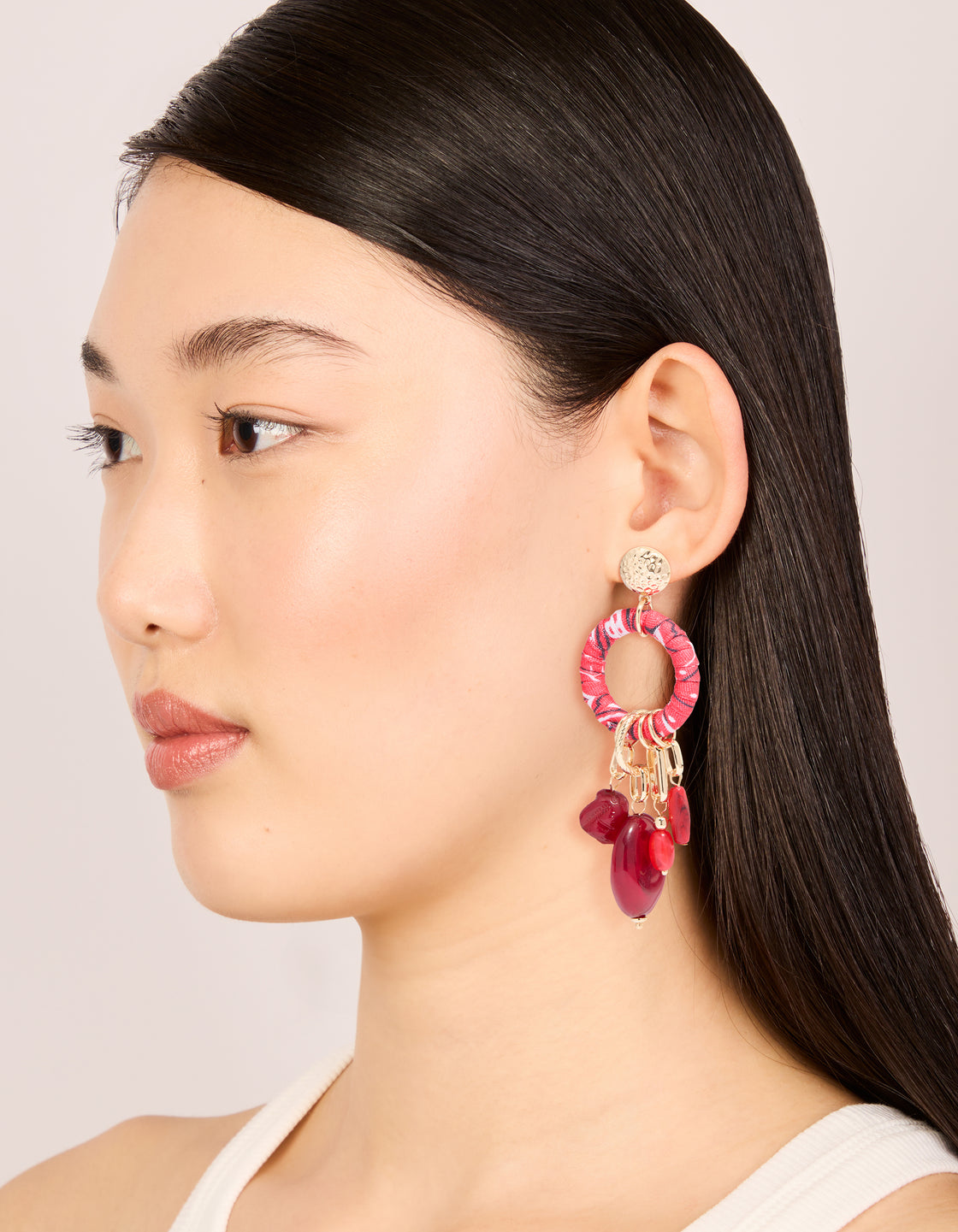 Styled on model, these gold red beaded paper wrapped drop earrings feature statement charm in maroon on model view