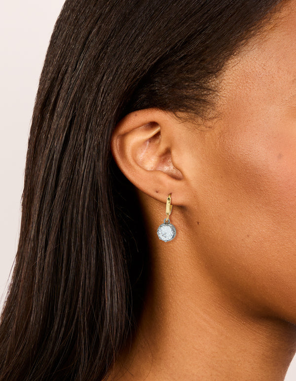 Featuring mixed metal plated cubic zirconia huggie drop earrings with hoop closure in silver and gold on ear view