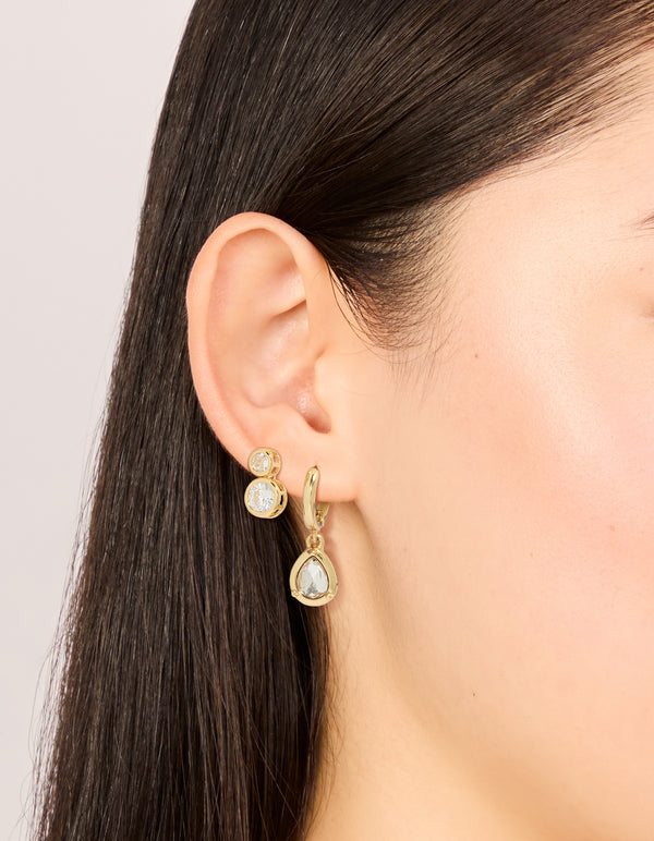 Showcasing large bezel set studs and huggie earrings 3-pack with cubic zirconia in gold plated finish on ear view