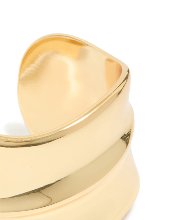 Featuring a gold plated wide organic wrist cuff with statement bangle design close up view
